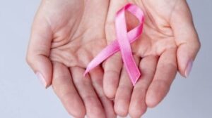 Mani ravvicinate che tengono un nastro rosa per sostenere il cancro al seno