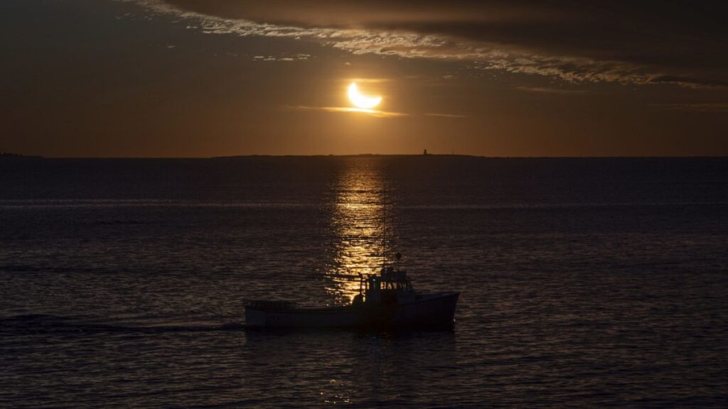 A fishing boat is silhouetted during a partial solar eclipse in Halifax on Saturday, March 29, 2025.