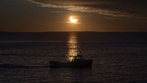 A fishing boat is silhouetted during a partial solar eclipse in Halifax on Saturday, March 29, 2025.