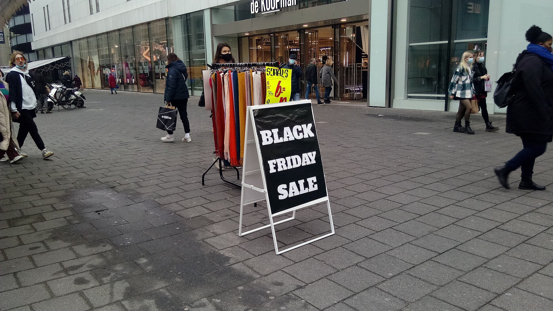 Cartello Black Friday Sale davanti a un negozio di abbigliamento in una via dello shopping pedonale