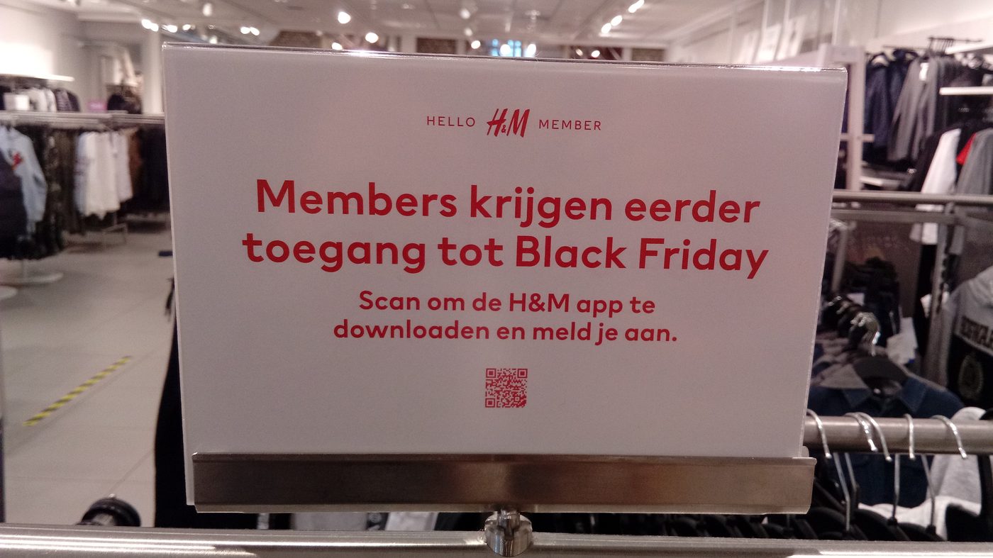 Cartello che annuncia l'accesso anticipato al Black Friday esposto su uno stand di abiti in un negozio di abbigliamento
