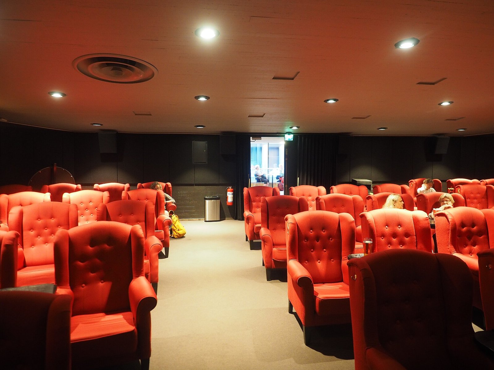 Sala cinematografica con poltrone rosse imbottite disposte a gradinata davanti allo schermo