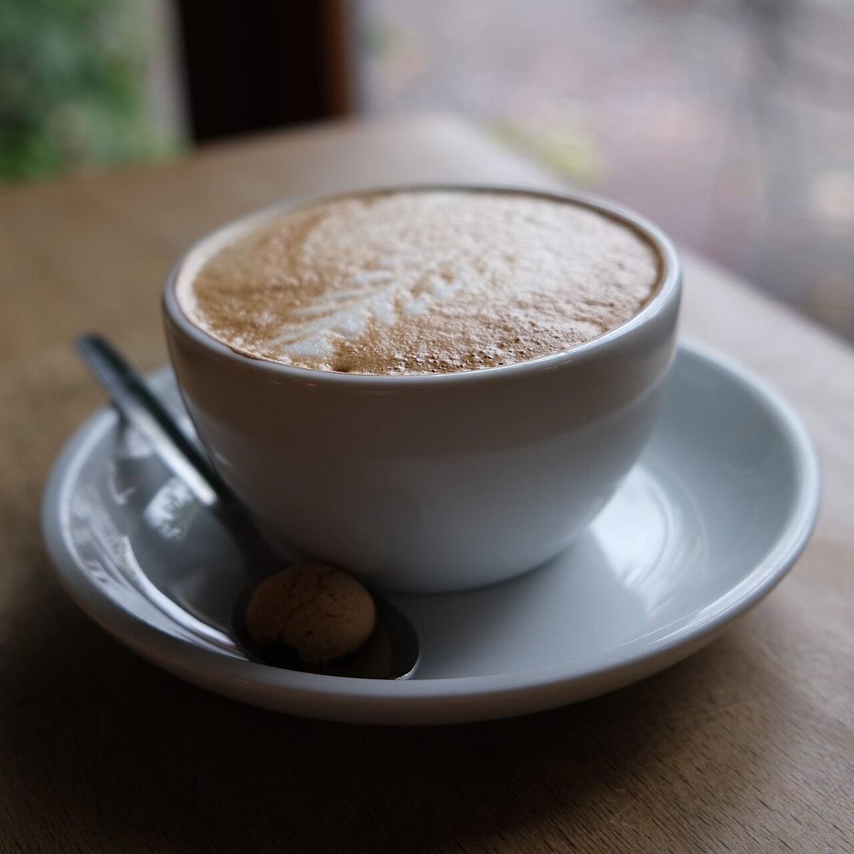 Tazza di cappuccino su un tavolino di un bar, la caffeina va limitata nel pomeriggio per non disturbare il sonno