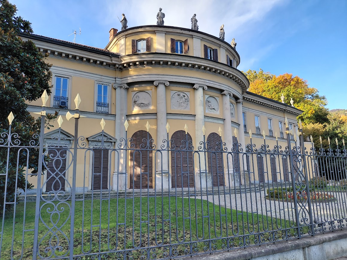 Facciata neoclassica di Villa Saporiti a Como, detta la Rotonda, con statue sul tetto e cancellata in ferro battuto
